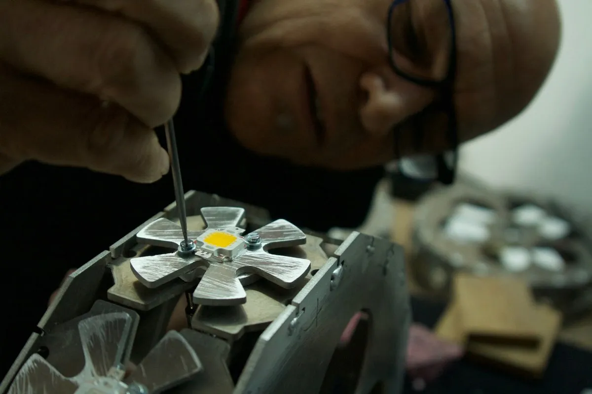 Técnico con gafas de aumento montando un chip LED sobre el disipador de una luminaria